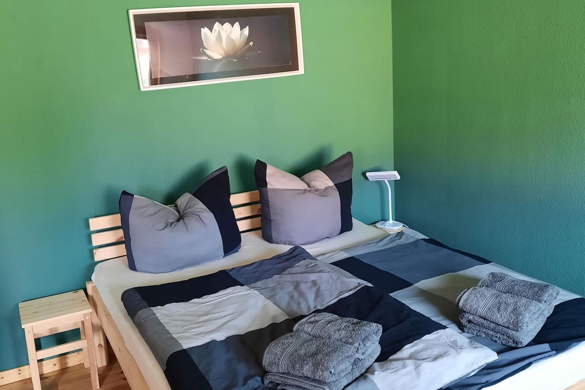A bed with a quilt, pillows, and a bedside table.