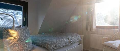 Ein Schlafzimmer mit einem Bett, einem Sessel und einem Fenster.