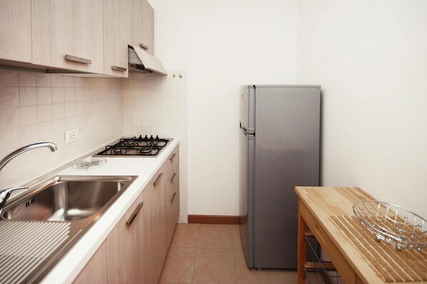 A compact kitchen with a stainless steel sink, a gas stove, and a built-in refrigerator. - Apartment in Lignano Sabbiadoro Near Cafe (Lignano Sabbiadoro)