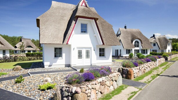 A row of white houses with thatched roofs and stone walls, surrounded by gravel and plants. - Holiday House, Fuhlendorf (Fuhlendorf)