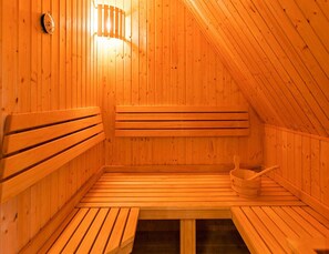 A wooden sauna with benches and a bucket. - Holiday House, Fuhlendorf (Fuhlendorf)
