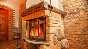 Una chimenea de piedra con leña encendida, una puerta de madera y un suelo de baldosas.