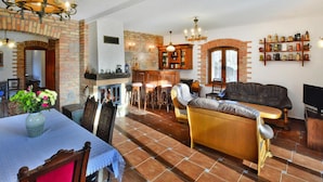 Amplia sala de estar con chimenea, comedor con mesa y sillas, y cocina con pared de ladrillo y muebles de madera.