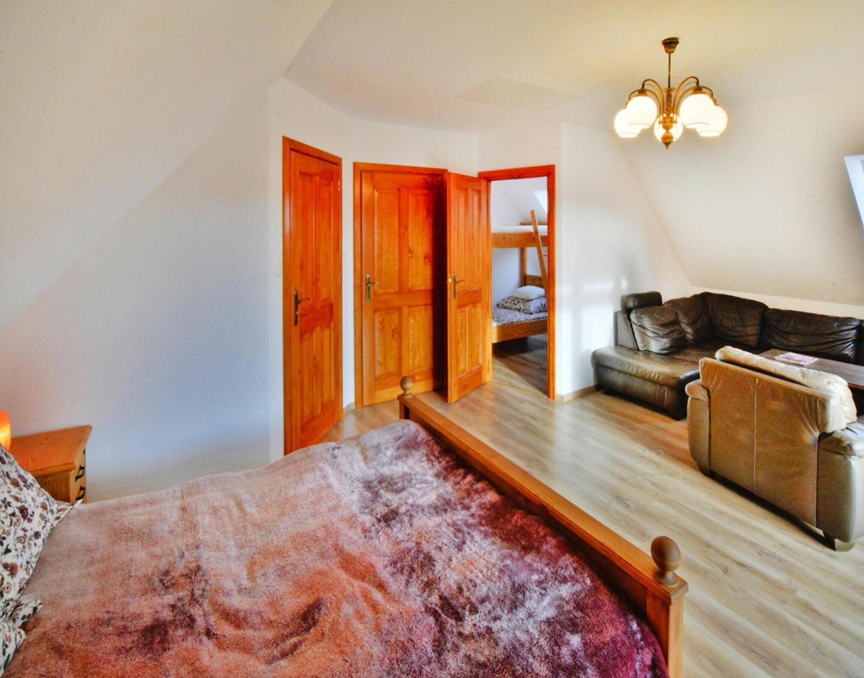 Ein Schlafzimmer mit einem großen Bett, einer hölzernen Bank, einer Couch und einem Etagenbett.
