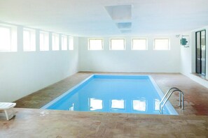 A rectangular indoor swimming pool with a tiled floor and a metal ladder. - Bungalow in Bezecca With Swimming Pool (Ledro)