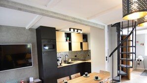 Eine moderne Küche mit Essbereich, einem Fernseher und einer Treppe.