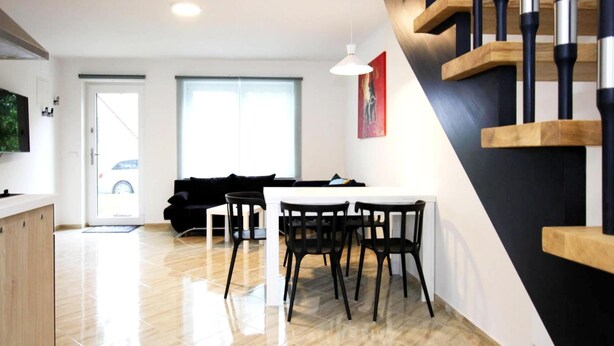 A modern living space with a dining area, a staircase, and a kitchen.