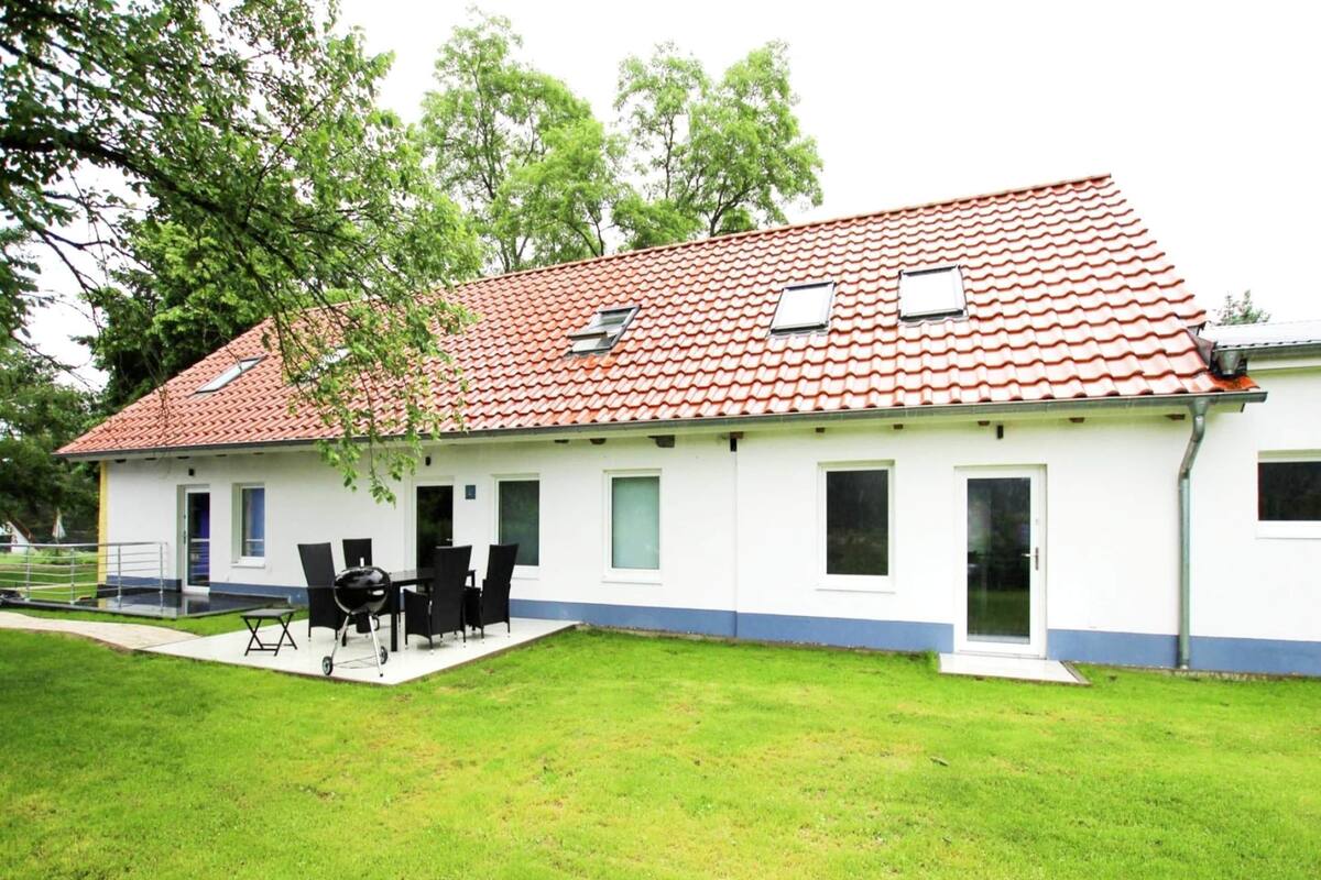 A two-story house with a red-tiled roof, a patio with outdoor furniture, and a well-maintained lawn.