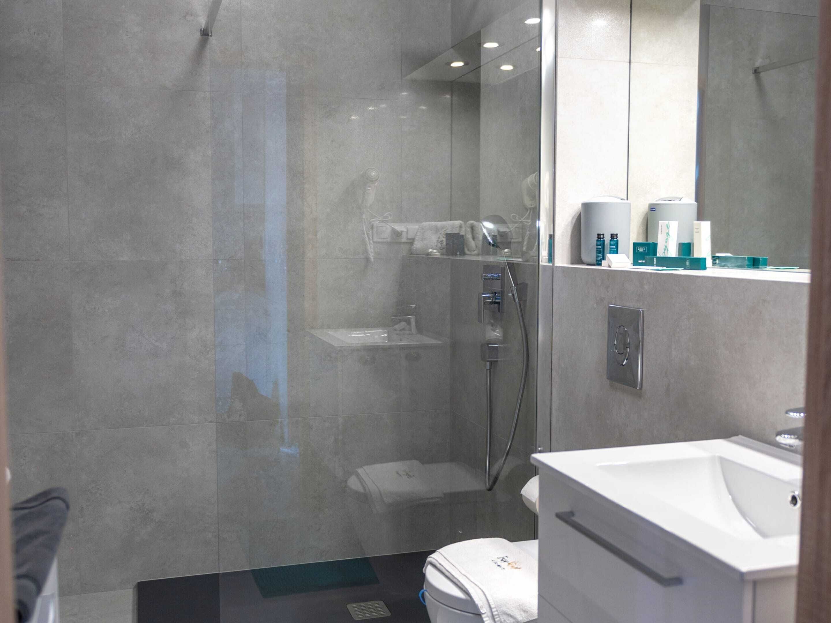 A modern bathroom with a glass-enclosed shower, a white sink, and a mirror above the sink.
