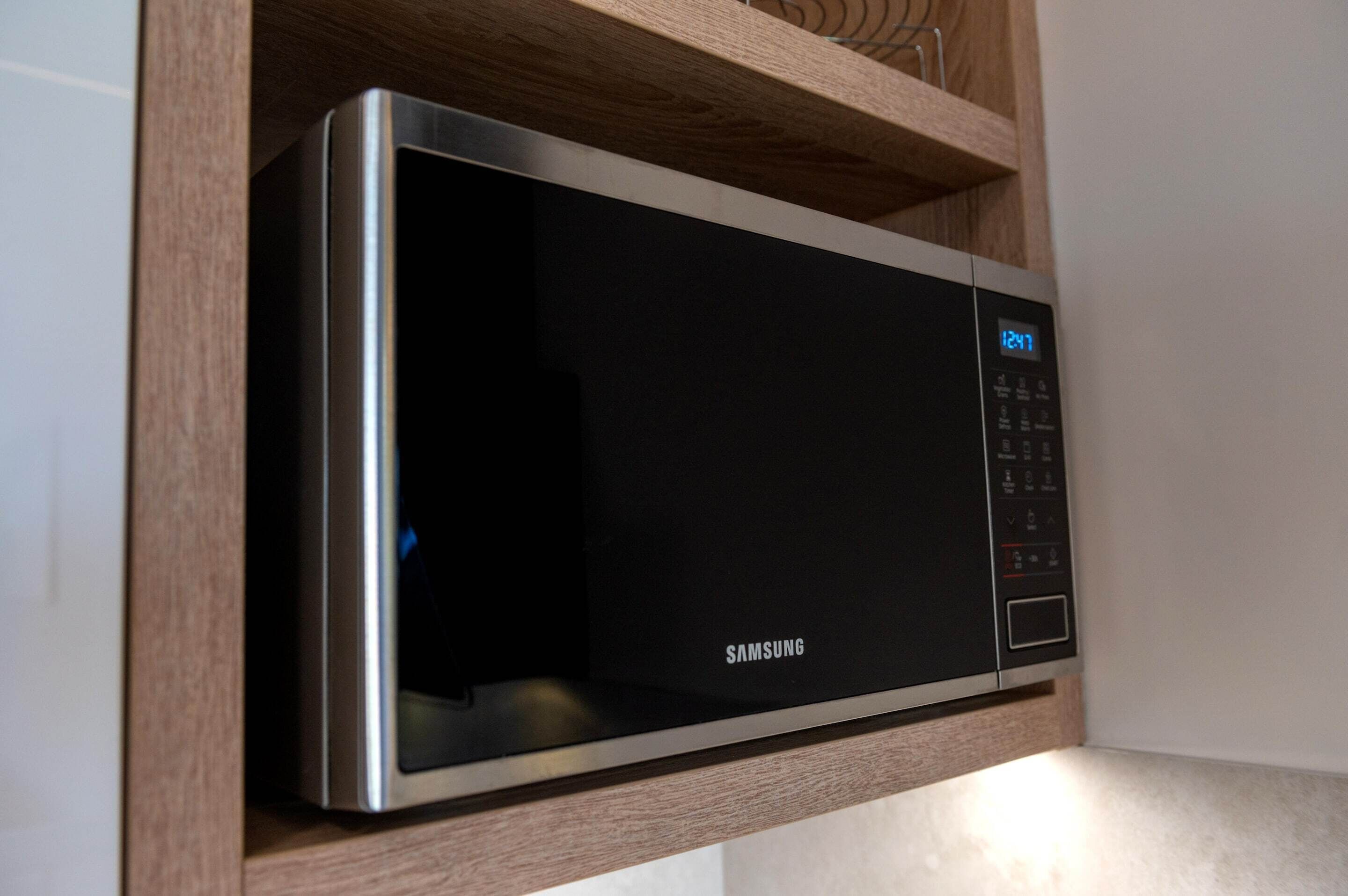 A Samsung microwave in a wooden cabinet.