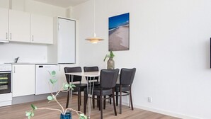 Eine moderne Küche mit weißen Schränken, einem weißen Kühlschrank und einem Essbereich mit Tisch und Stühlen.