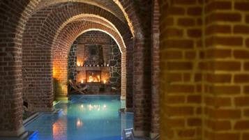 An indoor swimming pool with brick arches and a stone fireplace.
