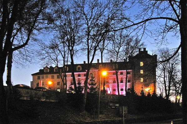 A large building with multiple windows and a prominent tower, surrounded by trees and a streetlight. - Apartment Right on the Lake, Ryn (Ryn)