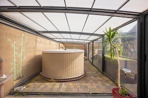 A spa area with a hot tub, bamboo wall art, and potted plants.