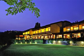 A multi-story hotel with a well-lit exterior, a landscaped front yard, and a clear view of the surrounding landscape. - Apartments Poiano in Garda With Pool (Garda)