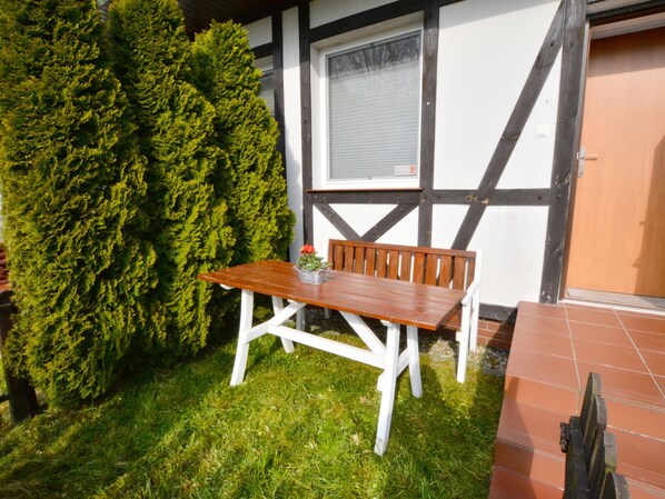 A wooden bench with a white frame, a small potted plant, and a window with blinds. - Cozy Cottage for 2 People Near the Sandy Beach (gmina Bedzino)