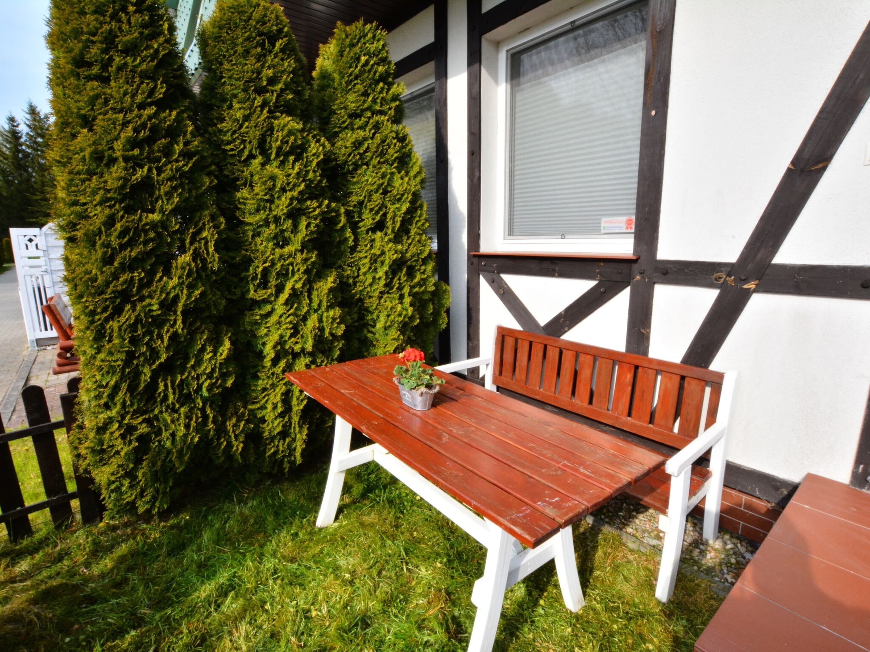 A wooden table and bench set outdoors with a potted plant on the table.