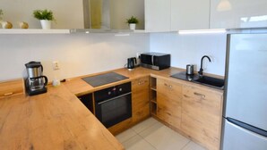 A modern kitchen with wooden countertops, a built-in oven, a microwave, a coffee maker, and a refrigerator. - Cozy Cottage for 2 People Near the Sandy Beach (gmina Bedzino)