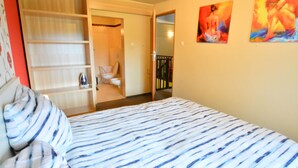 A bedroom with a bed, a wardrobe, and a bathroom visible through an open door. - Cozy Cottage for 2 People Near the Sandy Beach (gmina Bedzino)