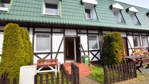 A traditional building with a green roof, multiple windows, and a wooden fence. - Cozy Cottage for 2 People Near the Sandy Beach (gmina Bedzino)