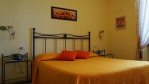 A bed with a metal frame, an orange bedspread, and two orange pillows. - Apartments Casa Tamas, Limone (Tremosine)