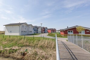A row of modern houses with a wooden walkway leading to a gated entrance. - Exclusively Furnished 5-star Holiday Home Near the Beach (Dagebuell)