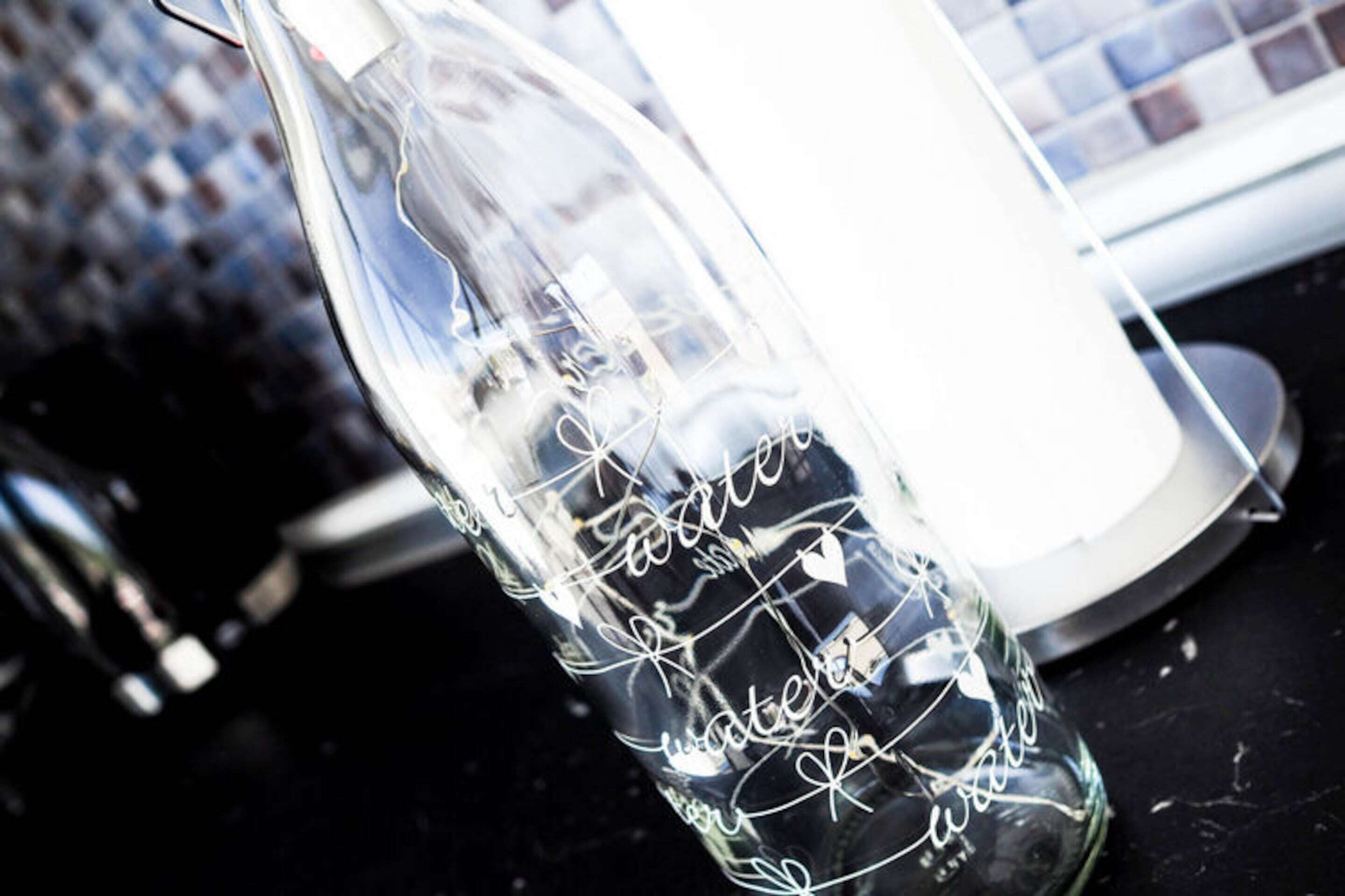 A clear glass bottle with engraved text and a heart symbol.