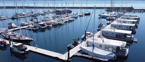 A marina with multiple boats docked at piers, a clear sky, and calm water.