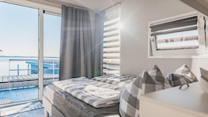 A bedroom with a bed, a window with blinds, a view of a dock, and a balcony. - Houseboat in Ribnitz-damgarten (Ribnitz-Damgarten)