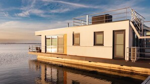 A modern, single-story boat with a flat roof, large windows, and a covered deck area. - Houseboat in Ribnitz-damgarten (Ribnitz-Damgarten)