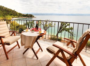 A terrace with a table set for two, overlooking a coastal view. - Splendid Beachfront Medveja Apartments (Lovran)