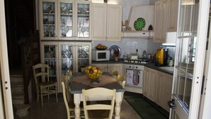 A kitchen with a dining table, chairs, cabinets, a microwave, stove, and a clock on the wall. - Lovely Villa in Castellammare del Golfo With Private Pool (Castellammare del Golfo)