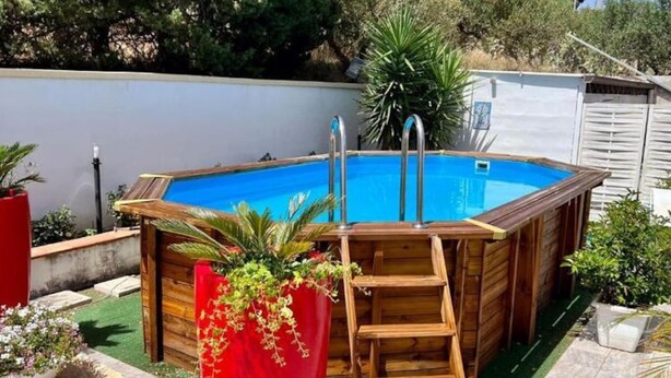 A rectangular wooden swimming pool with a ladder and metal handrails, surrounded by a wooden deck and potted plants. - Lovely Villa in Castellammare del Golfo With Private Pool (Castellammare del Golfo)