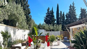 A patio area with white chairs, potted plants, and a wooden fence. - Lovely Villa in Castellammare del Golfo With Private Pool (Castellammare del Golfo)