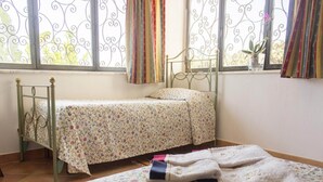 A bedroom with a single bed, a small table, and a window with curtains. - Lovely Villa in Castellammare del Golfo With Private Pool (Castellammare del Golfo)