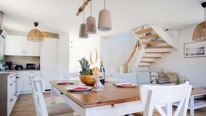 A modern kitchen with white cabinets, a wooden dining table, and hanging pendant lights. - Holiday Home With Sauna in Boiensdorf (Boiensdorf)