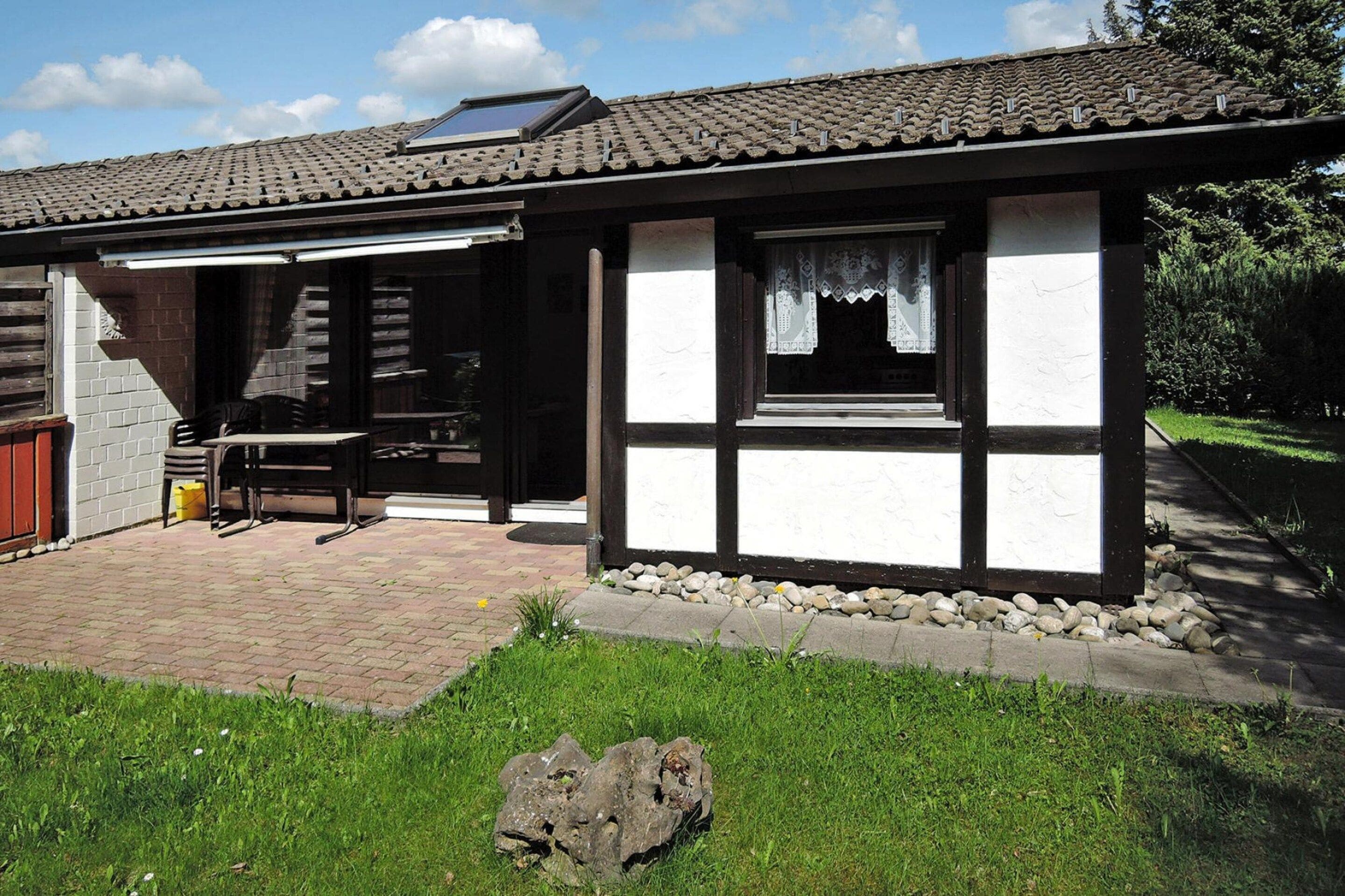 A traditional house with a tiled roof, a wooden door, and a small patio area with a table and chairs.
