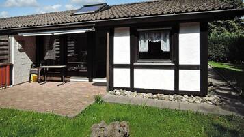 A traditional house with a tiled roof, a wooden door, and a small patio area with a table and chairs.