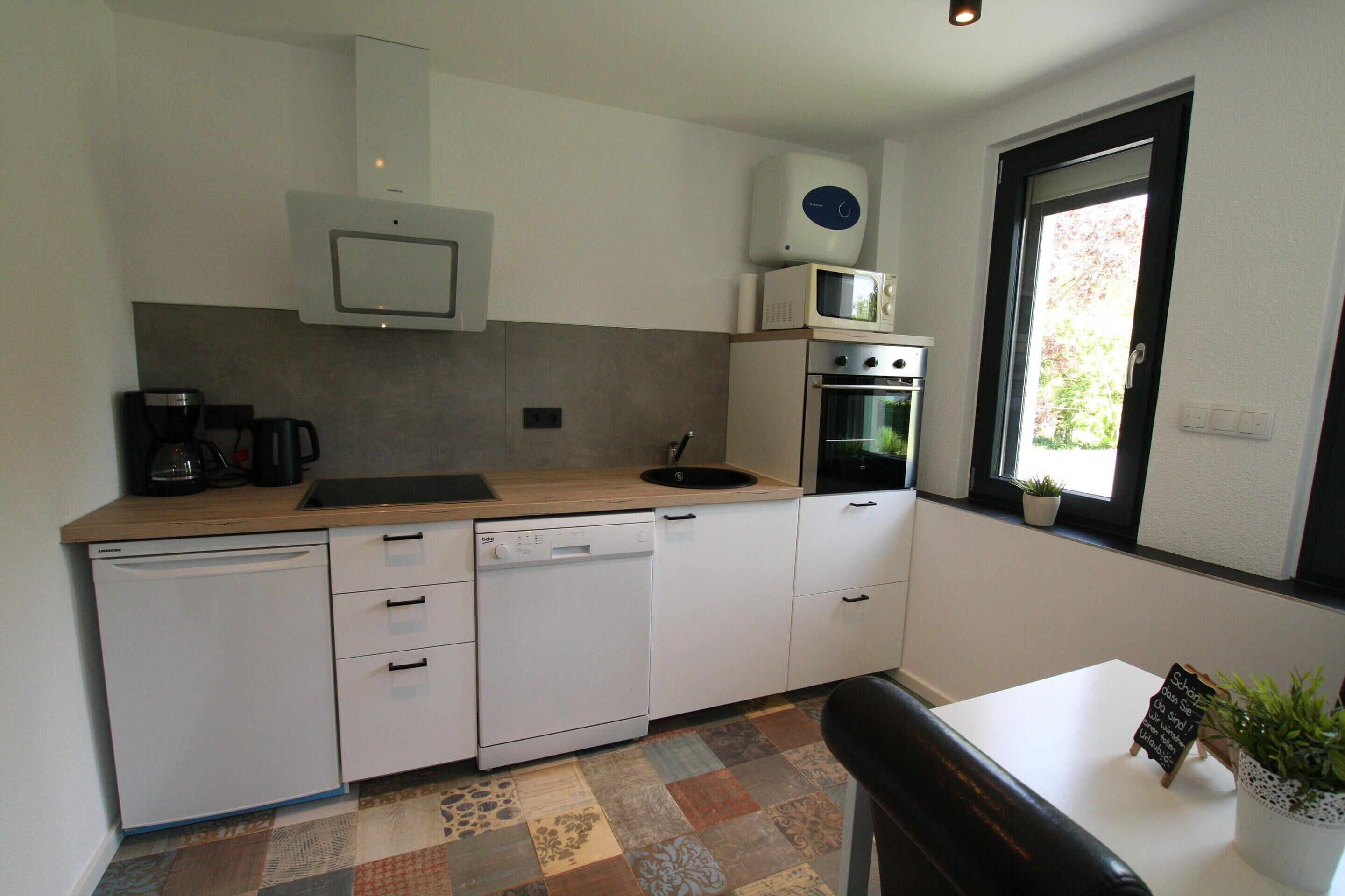A compact kitchen with white appliances, a coffee maker, and a window with a view.