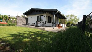 Et moderne hus med terrasse, grill og overdækket siddeområde.