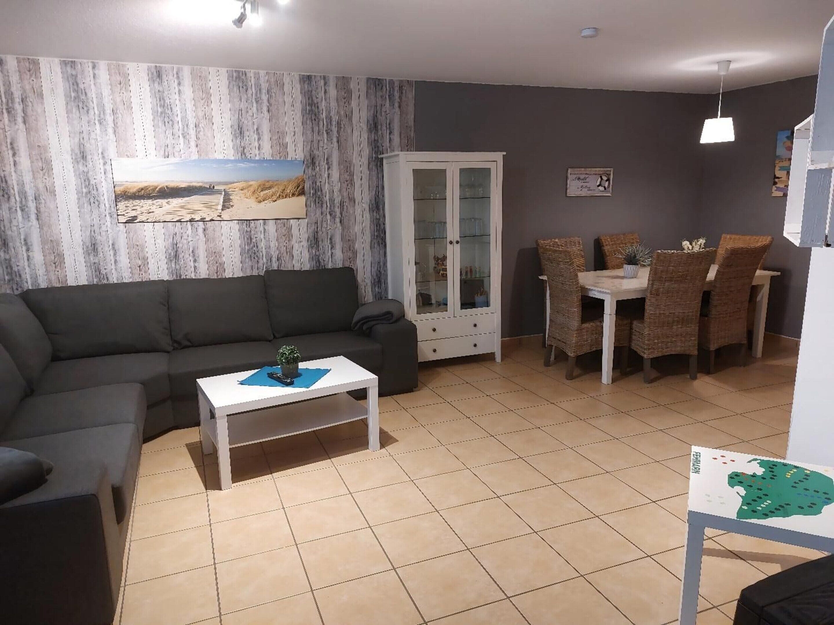Una sala de estar con un sofá, una mesita de centro, un aparador y un comedor con sillas.