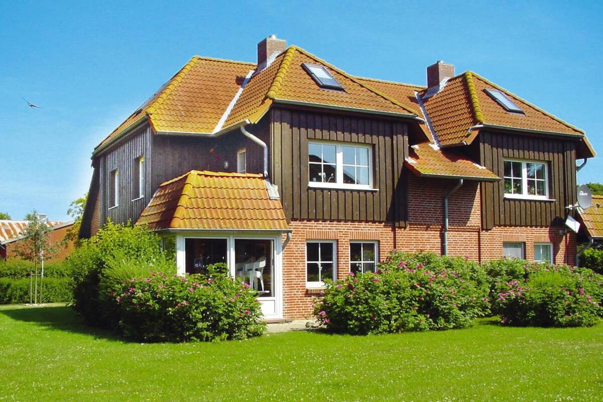 A two-story house with a sloped roof, a visible chimney, and a small porch with a glass door.