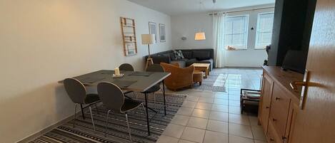A modern living room with a dining area, a sofa, a TV, and a fireplace.