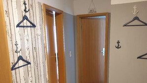 A hallway with a wooden door, a bench, and wall-mounted hangers. - Holiday Complex Wenkendorf, Fehmarn-wenkendorf (Fehmarn)