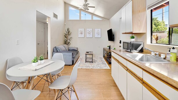 Una cucina moderna con zona pranzo, ventilatore a soffitto, televisore e una grande finestra.