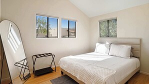 Una camera da letto con un letto, due finestre, un termosifone e una porta.
