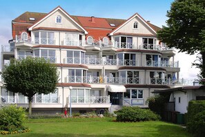 A multi-story building with balconies, a garden, and a flag. - Apartments Panorama With sea View Directly at the Beach Promenade of Laboe (Laboe)
