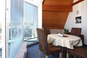 A dining area with a round table, brown upholstered chairs, and a white tablecloth. - Apartments Panorama With sea View Directly at the Beach Promenade of Laboe (Laboe)