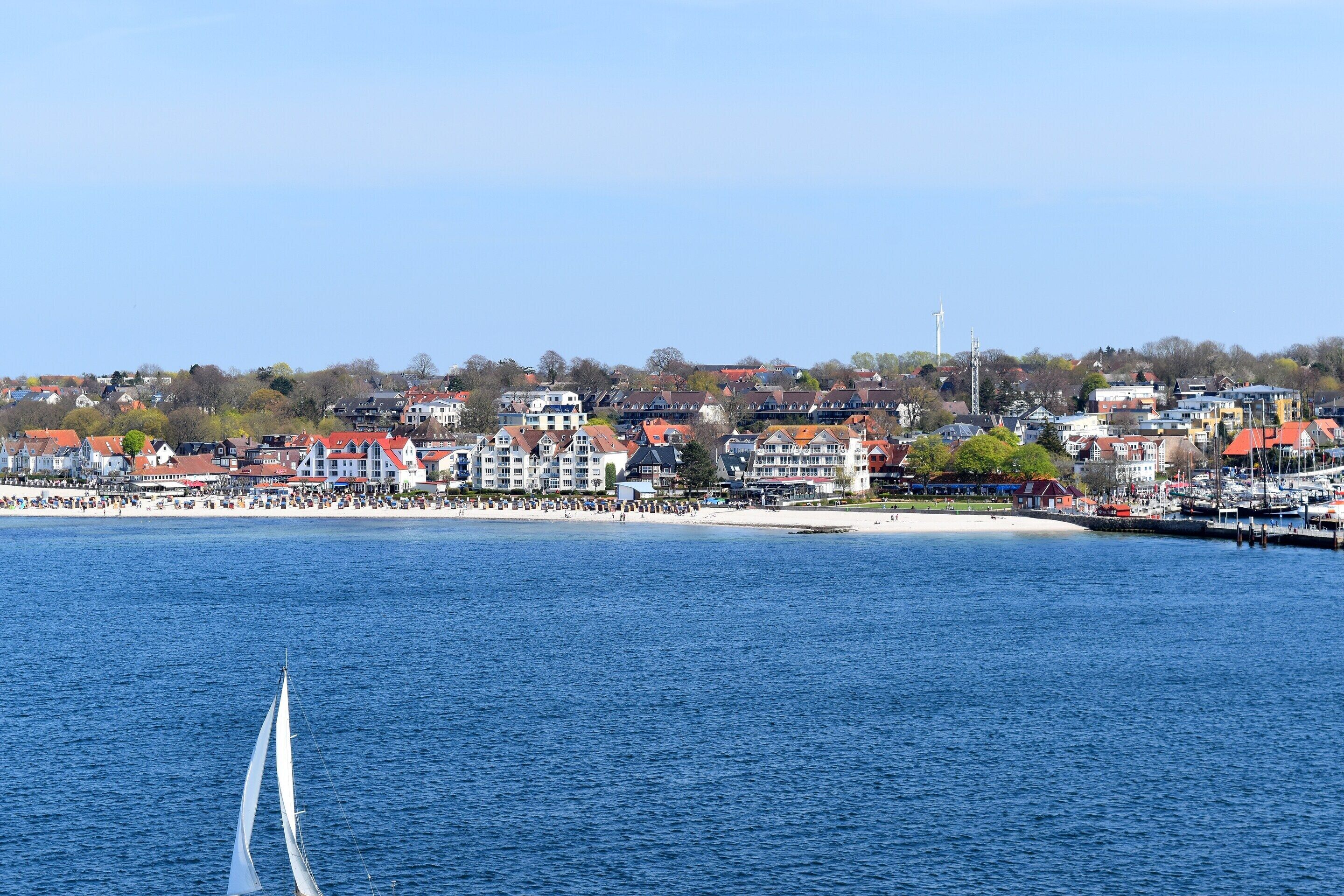 A coastal town with a marina and a sailboat in the foreground.