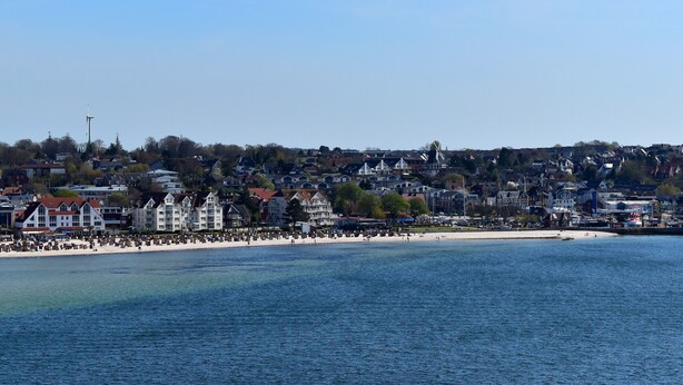 Een kustplaats met een strand, huizen en een windmolen.
